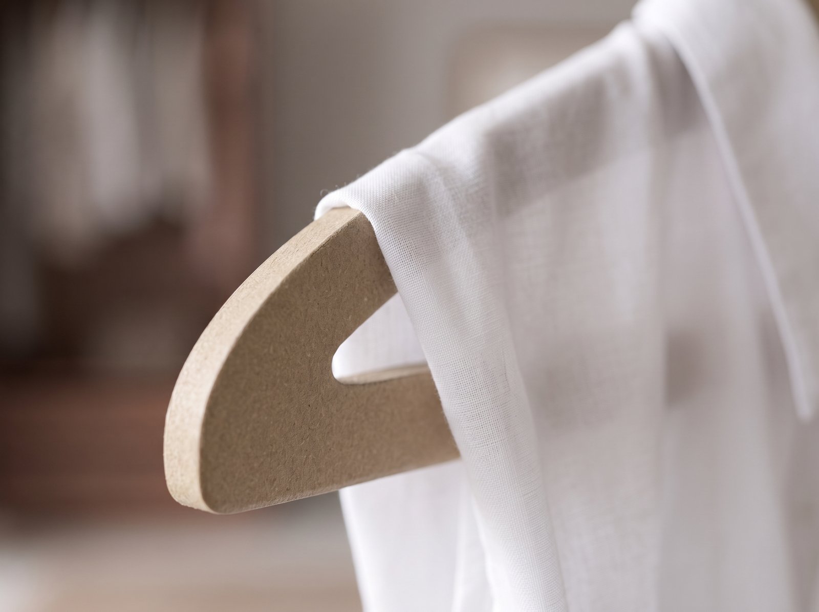 Gancho de cartón comprimido tipo madera con superficie lisa y sellada que cuida la ropa.